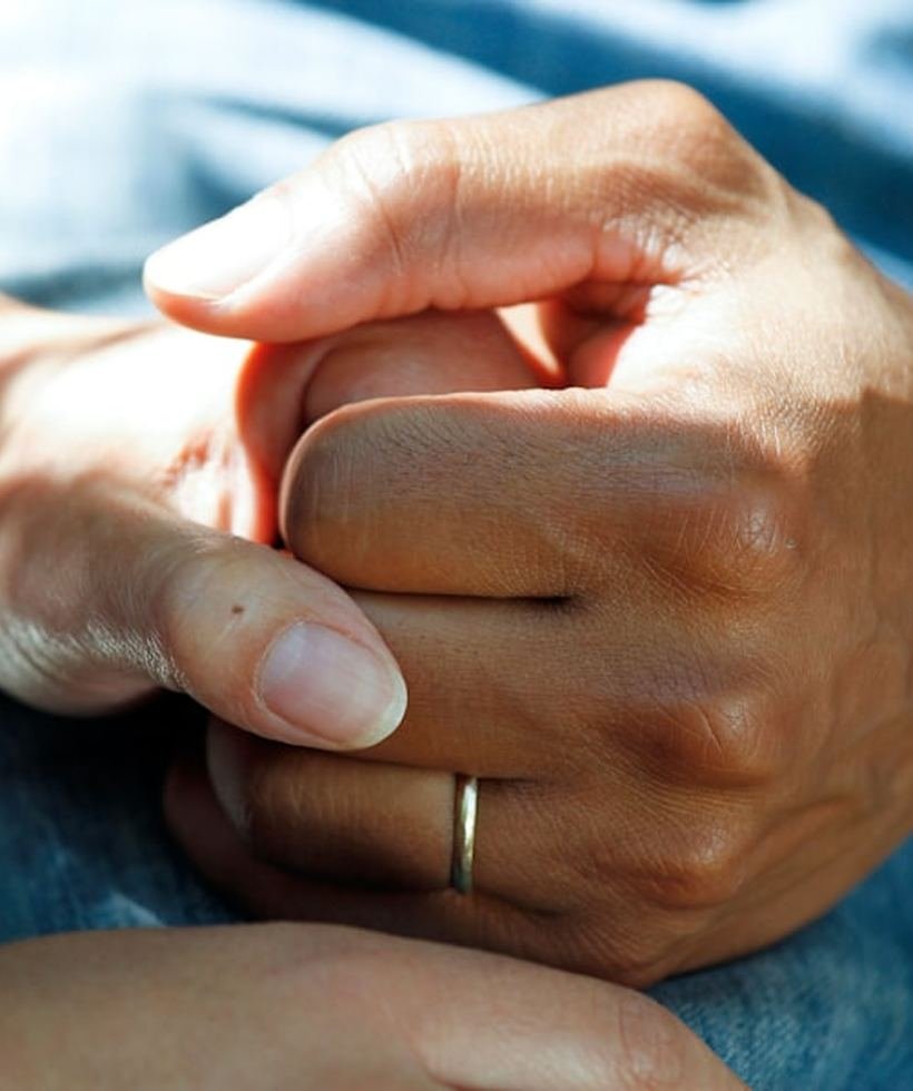 A caregiver gently holding a client's hands in comfort